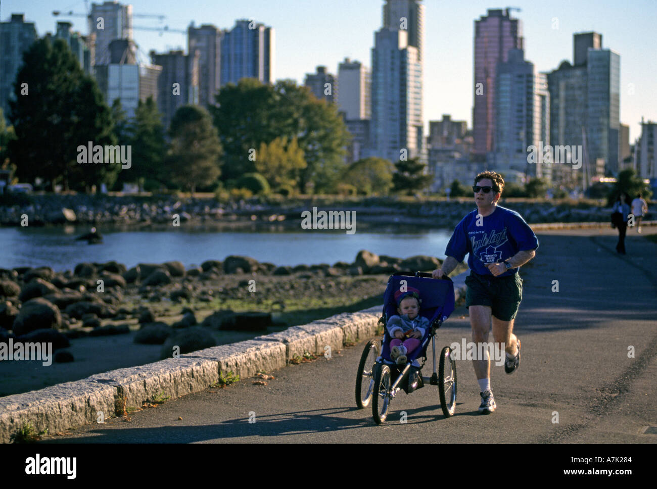 Homme qui court avec l'enfant dans la poussette Vancouver BC Canada Banque D'Images