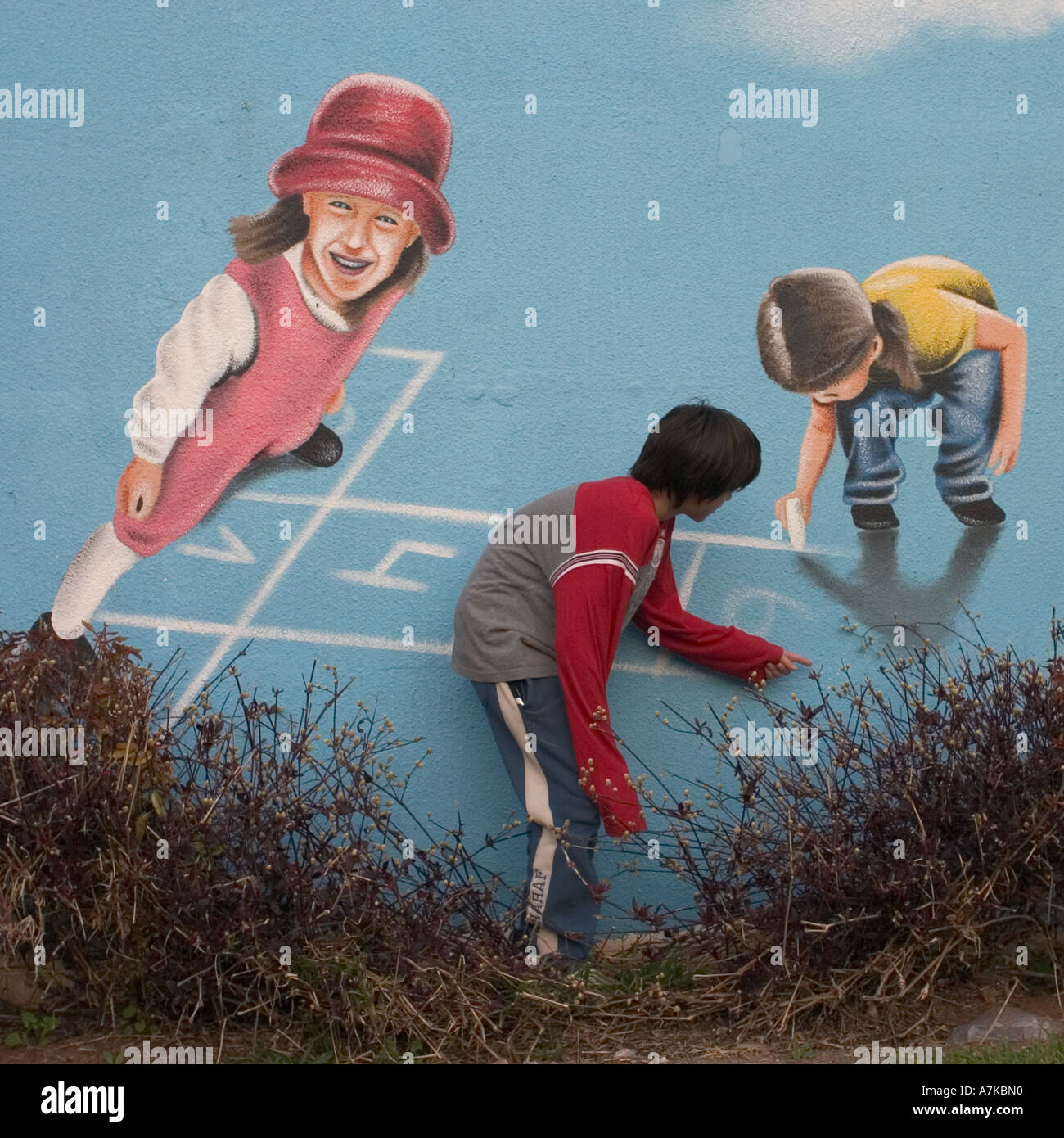 Un jeune garçon jouant avec une caricature sur un mur Banque D'Images