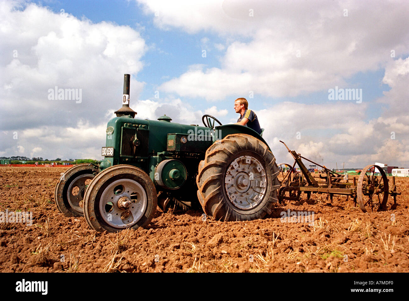 Une ancienne vintage tracteur laboure un champ de travail Banque D'Images