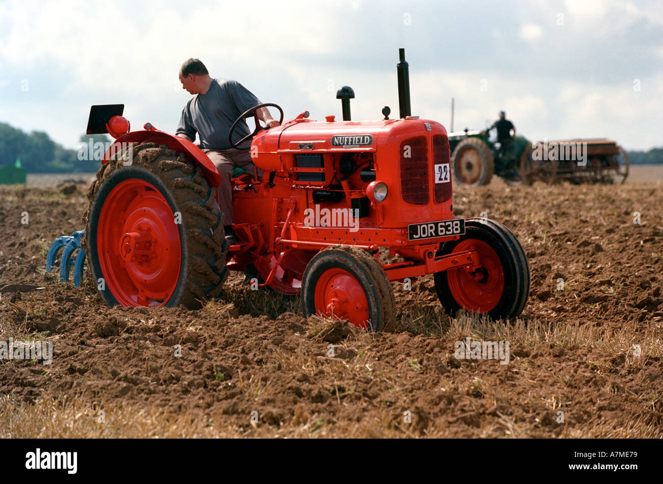 Une ancienne vintage tracteur laboure un champ de travail Banque D'Images