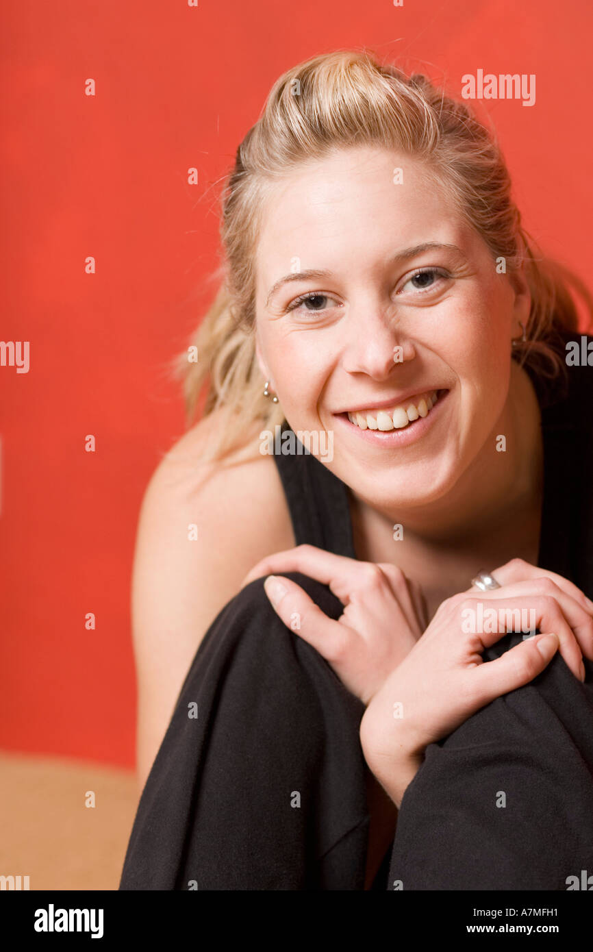 Jeune femme assis serrant les genoux Banque D'Images