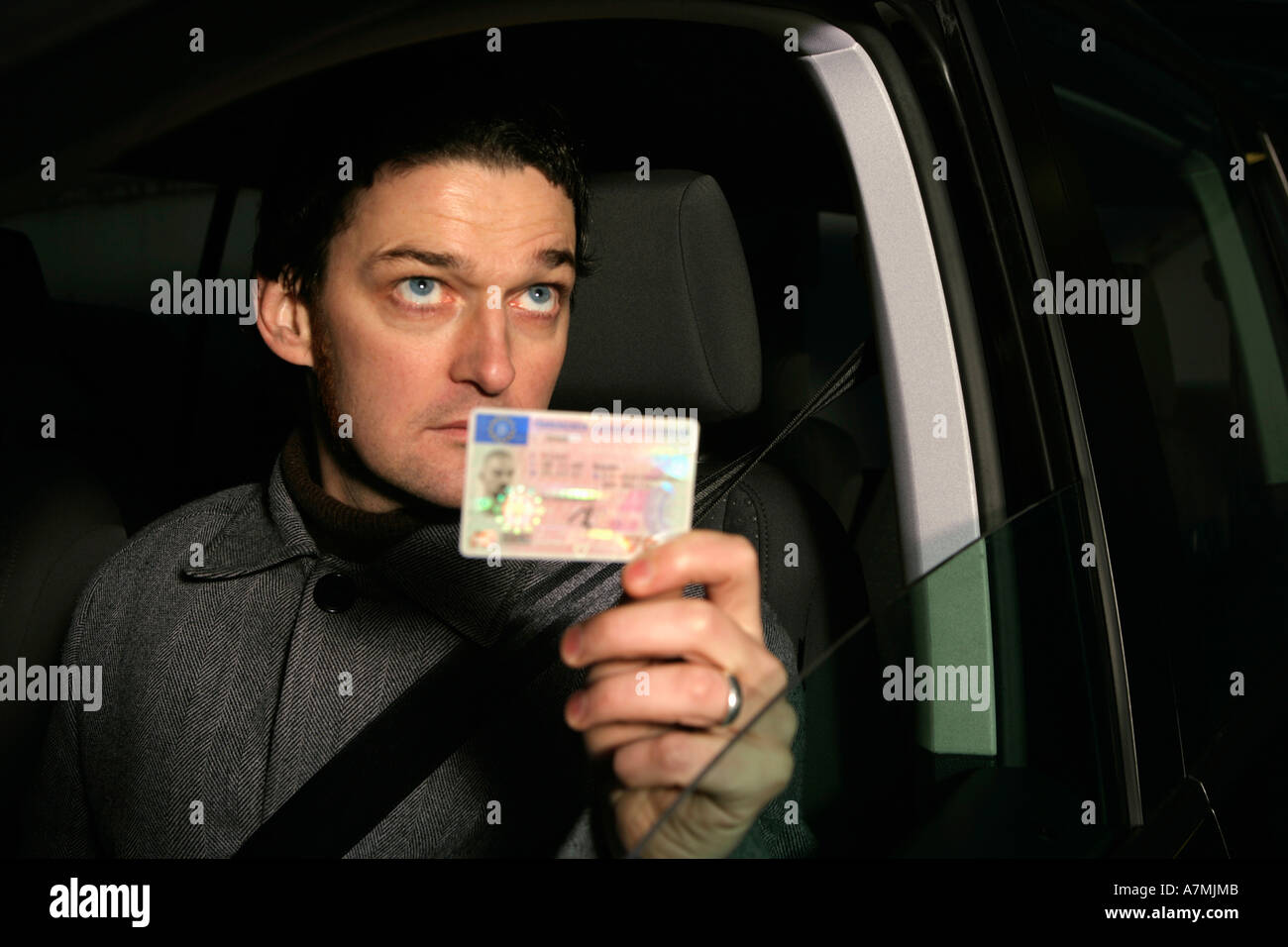 Homme assis dans la voiture et tenant sa carte d'identité Banque D'Images