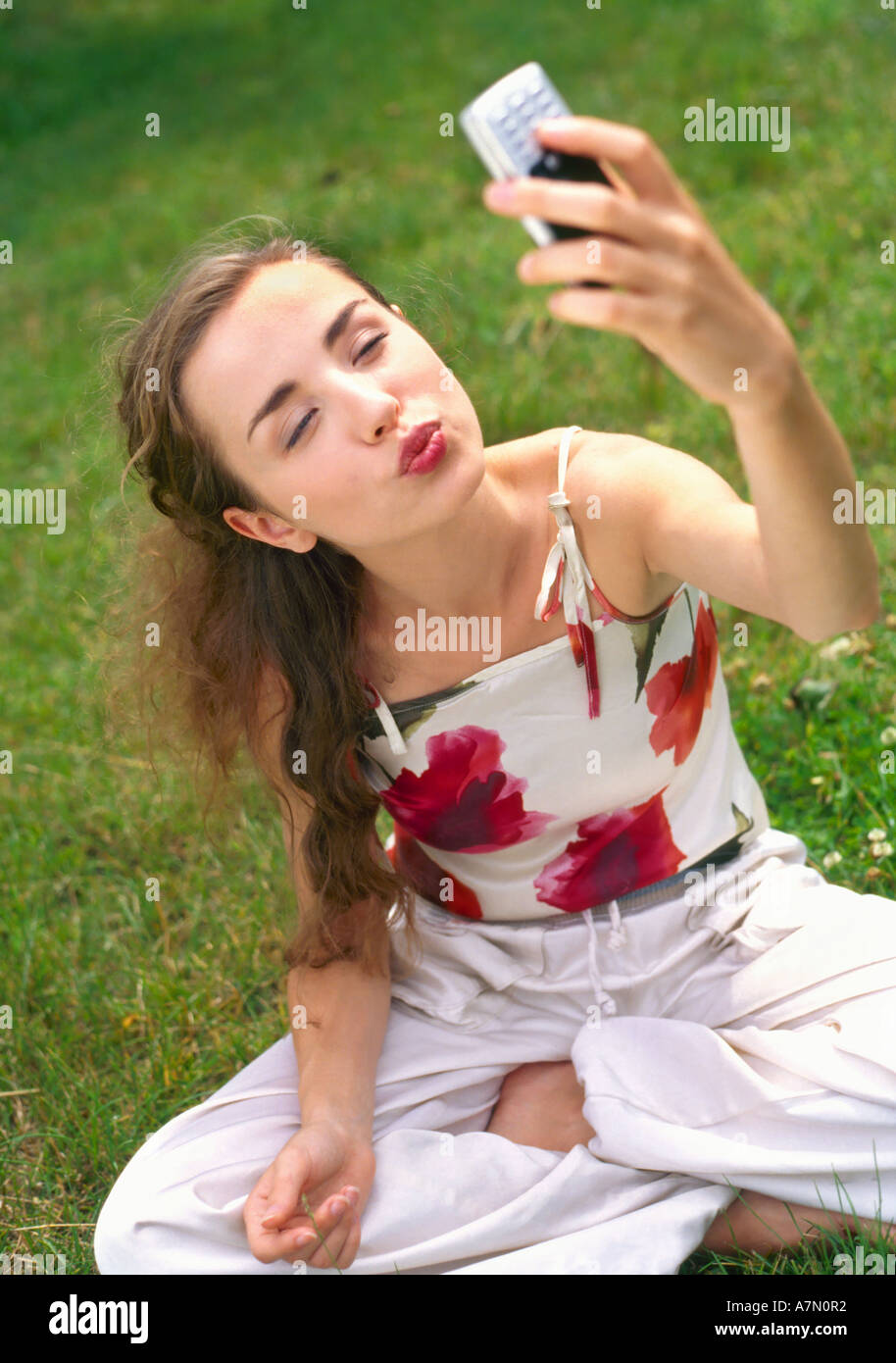 Journée plein air arbre arbres d'été femme fille prairie orchard 2025 jeune blonde long cheveux curl herbe sit trausers fleur haut rose ... Banque D'Images