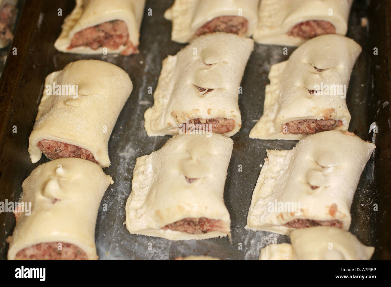 Petits rouleaux de saucisses faites maison, à l'état congelé sur la plaque de cuisson pour la cuisson. Banque D'Images