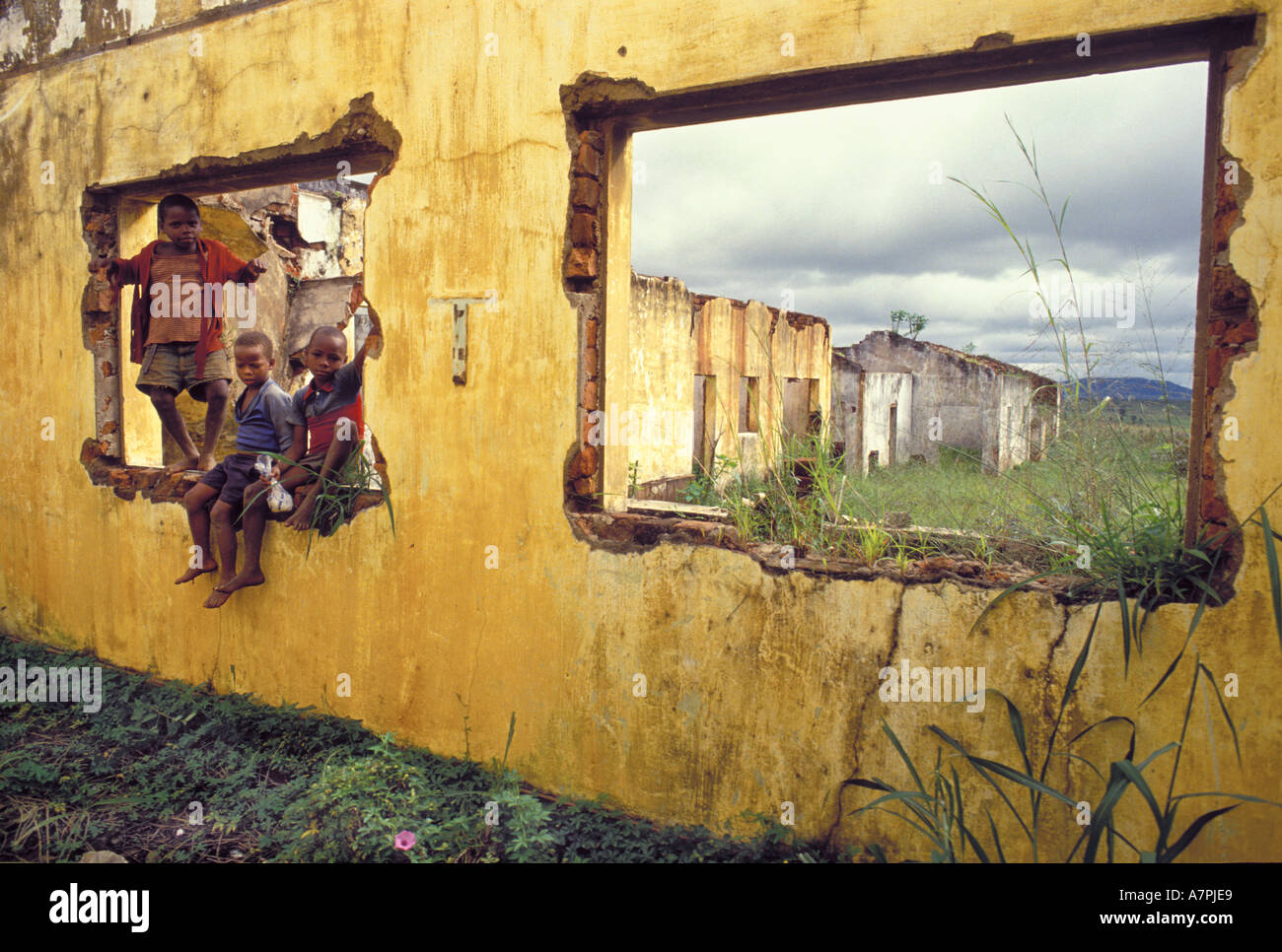 Les enfants africains jouent dans la fenêtre de ruines de bâtiments détruits dans la destruction de la guerre au Mozambique Banque D'Images