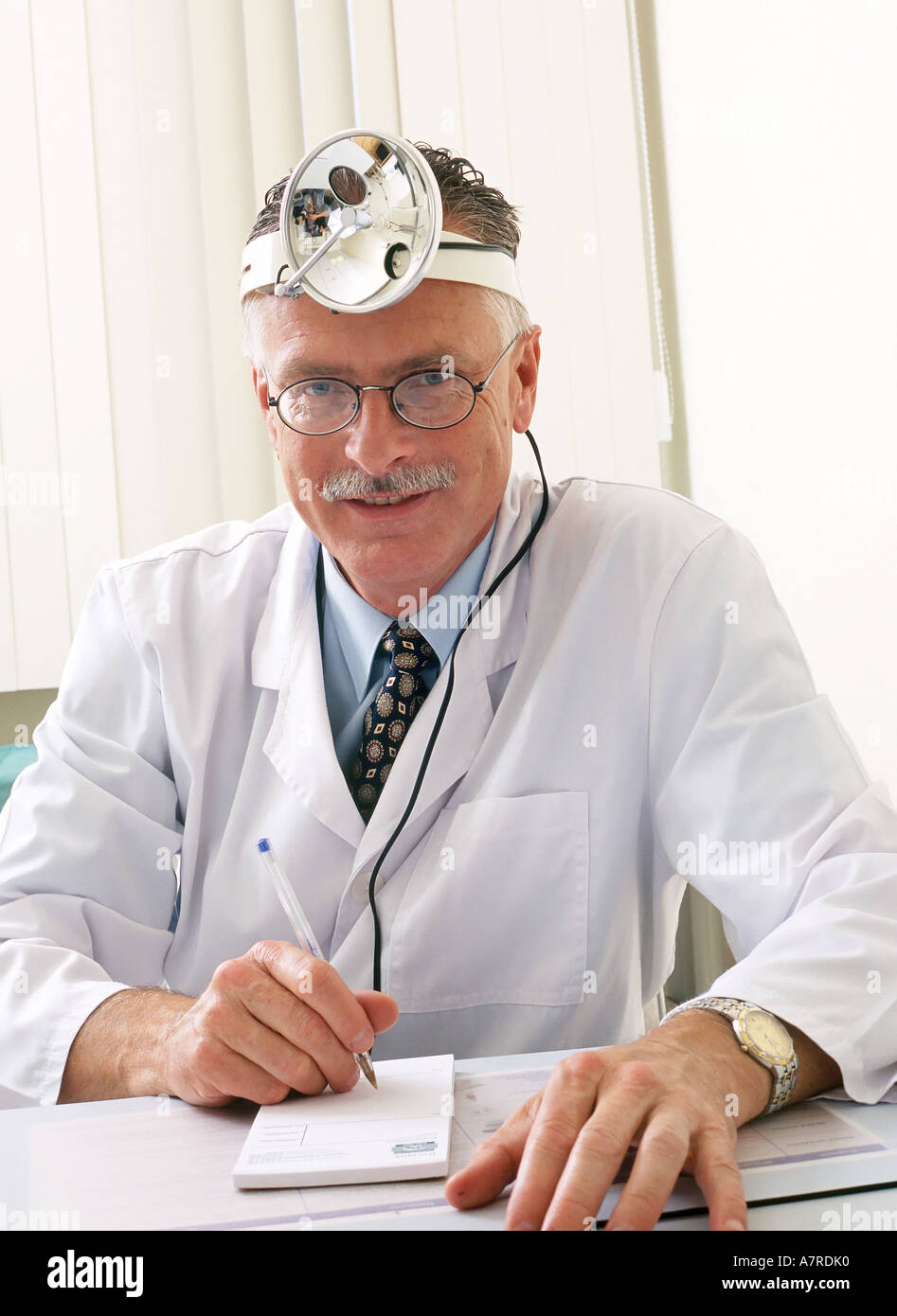 À l'intérieur du cabinet ambulatoire mature man 4550 moustache aux cheveux gris sourire souriant médecin laryngologist lunettes médicales robe sit Banque D'Images