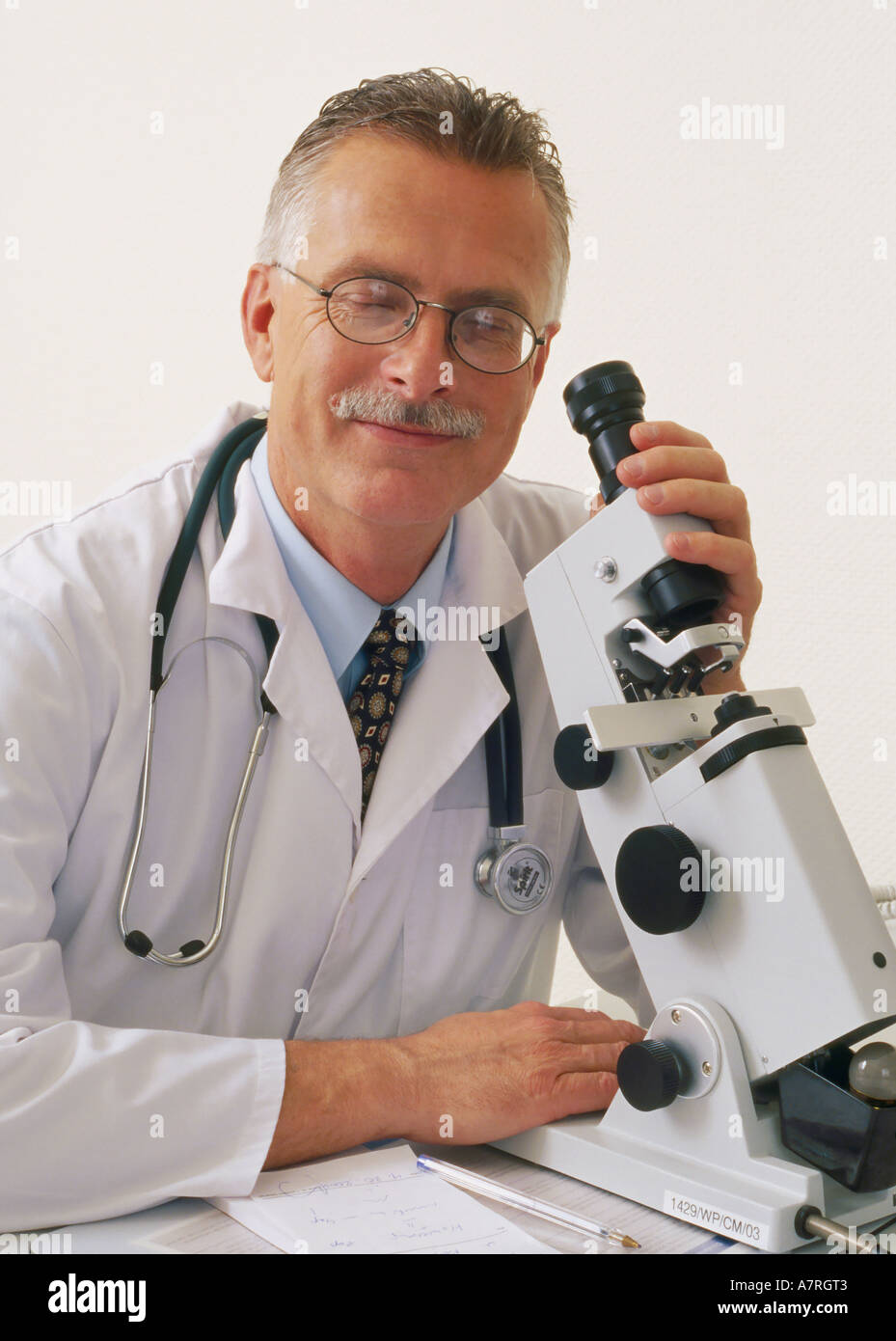 À l'intérieur du cabinet ambulatoire mature homme aux cheveux gris 4550 robe lunettes moustache stéthoscope médecin regarder sourire sonde microscope Banque D'Images