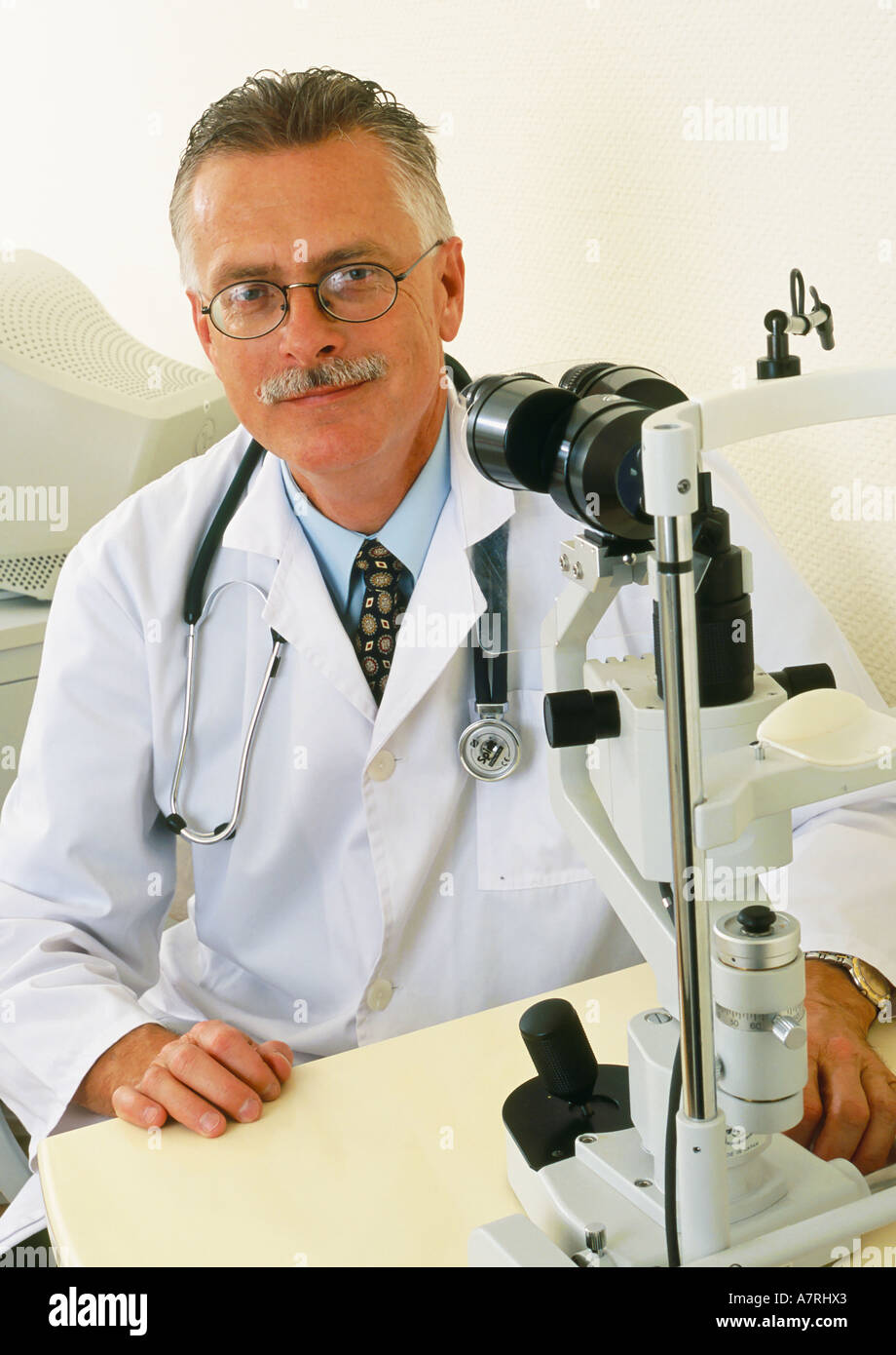 À l'intérieur du cabinet ambulatoire mature homme aux cheveux gris 4550 lunettes moustache sourire souriant médecin ophtalmologiste optomerist robe Banque D'Images