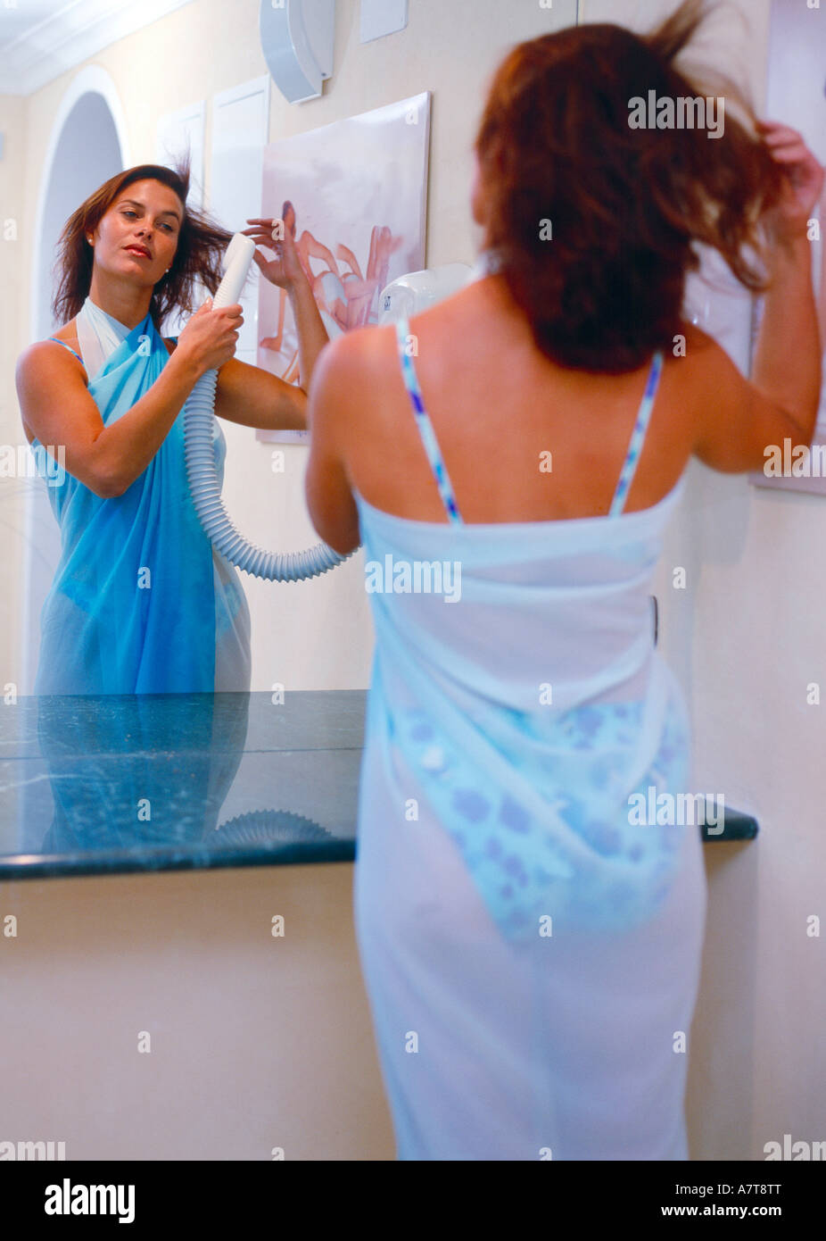 Reflet de jeune femme sécher ses cheveux dans un miroir Banque D'Images