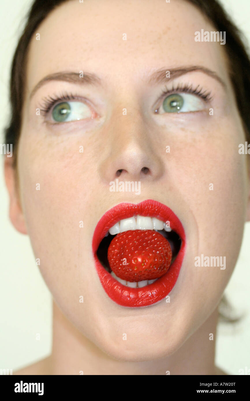 Jeune femme tenant dans la bouche de fraise Banque D'Images