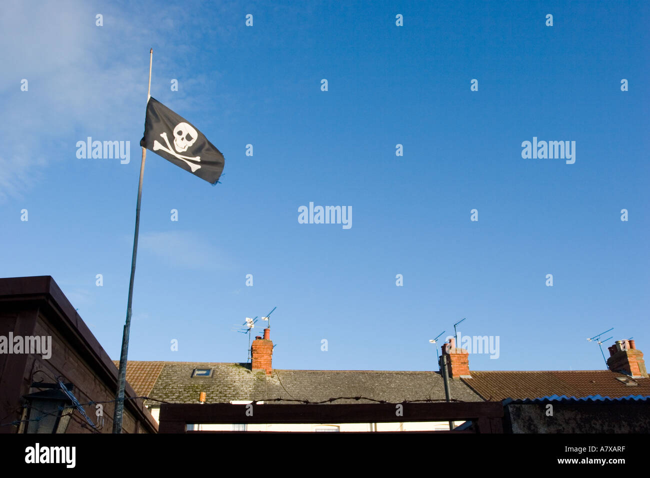 Drapeau pirate Jolly Roger survolant les toits en terrasse Banque D'Images
