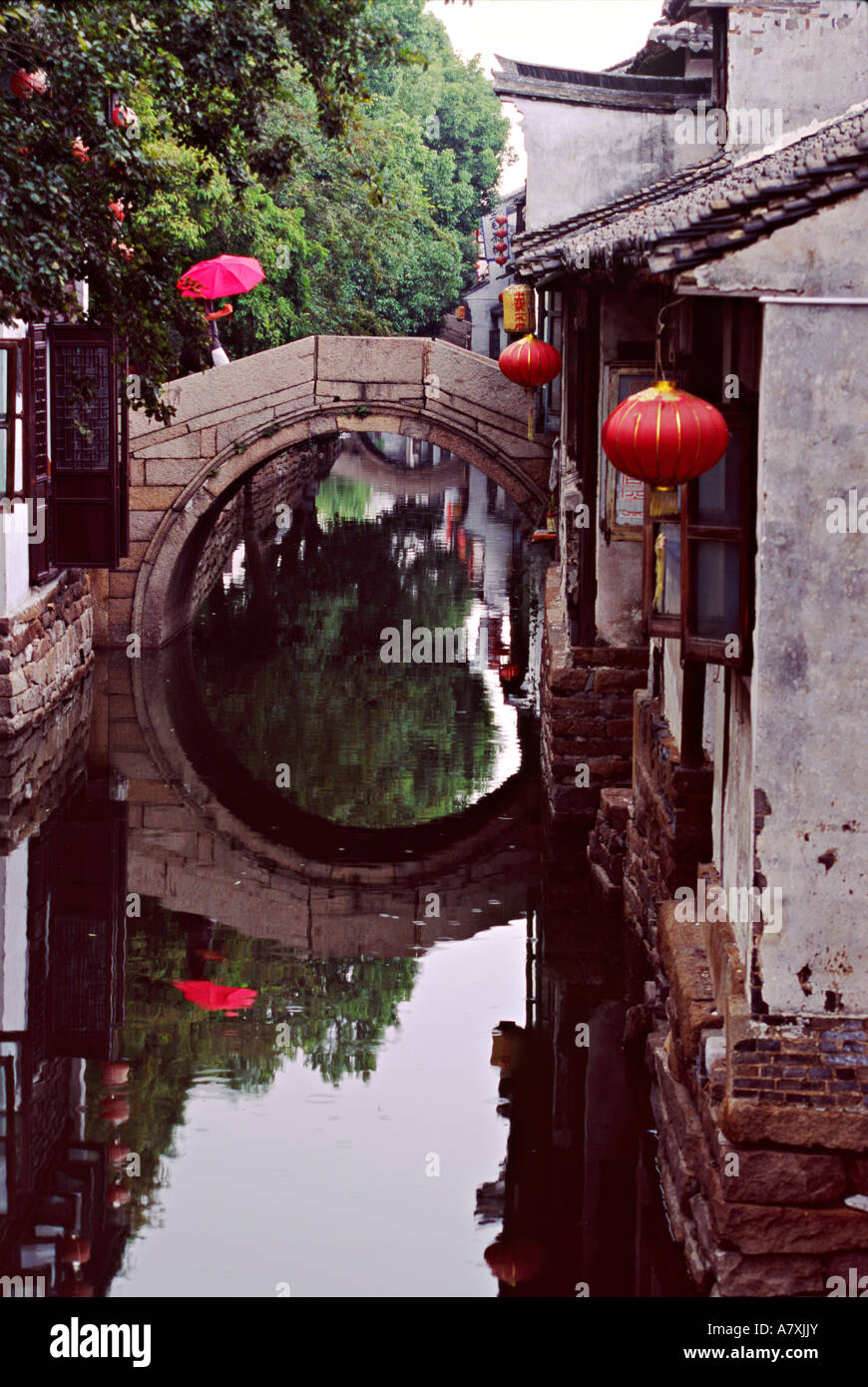 L'Asie, Chine, Shanghai, China. Parapluie rouge sur le pont de pierre en arc au-dessus du canal de la vieille ville Banque D'Images