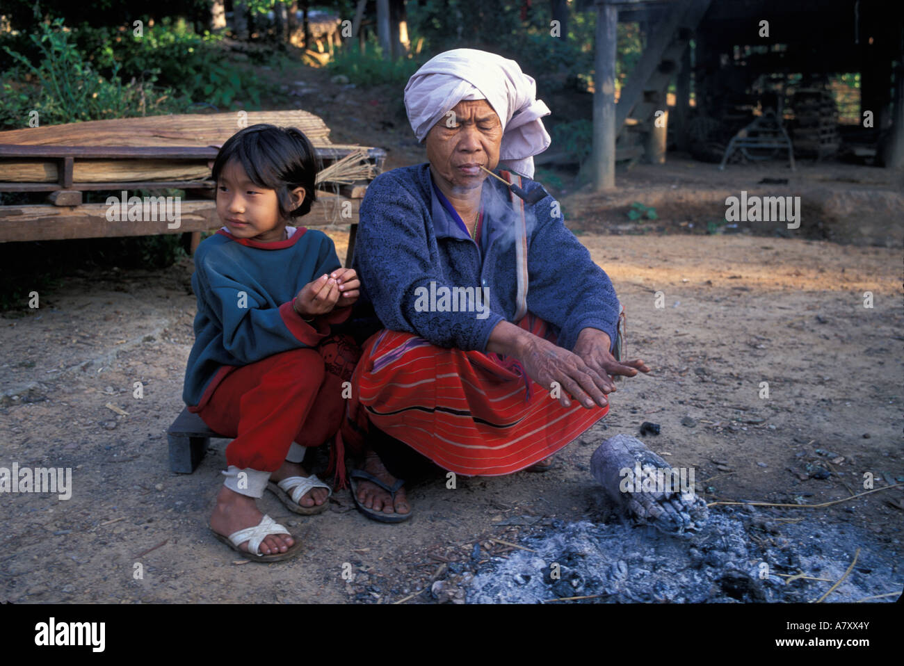 La Thaïlande, le parc national de Doi Inthanon, vieille femme et sa petite-fille s'asseoir par un incendie le matin d'hiver dans la région de Karen Hill village Banque D'Images