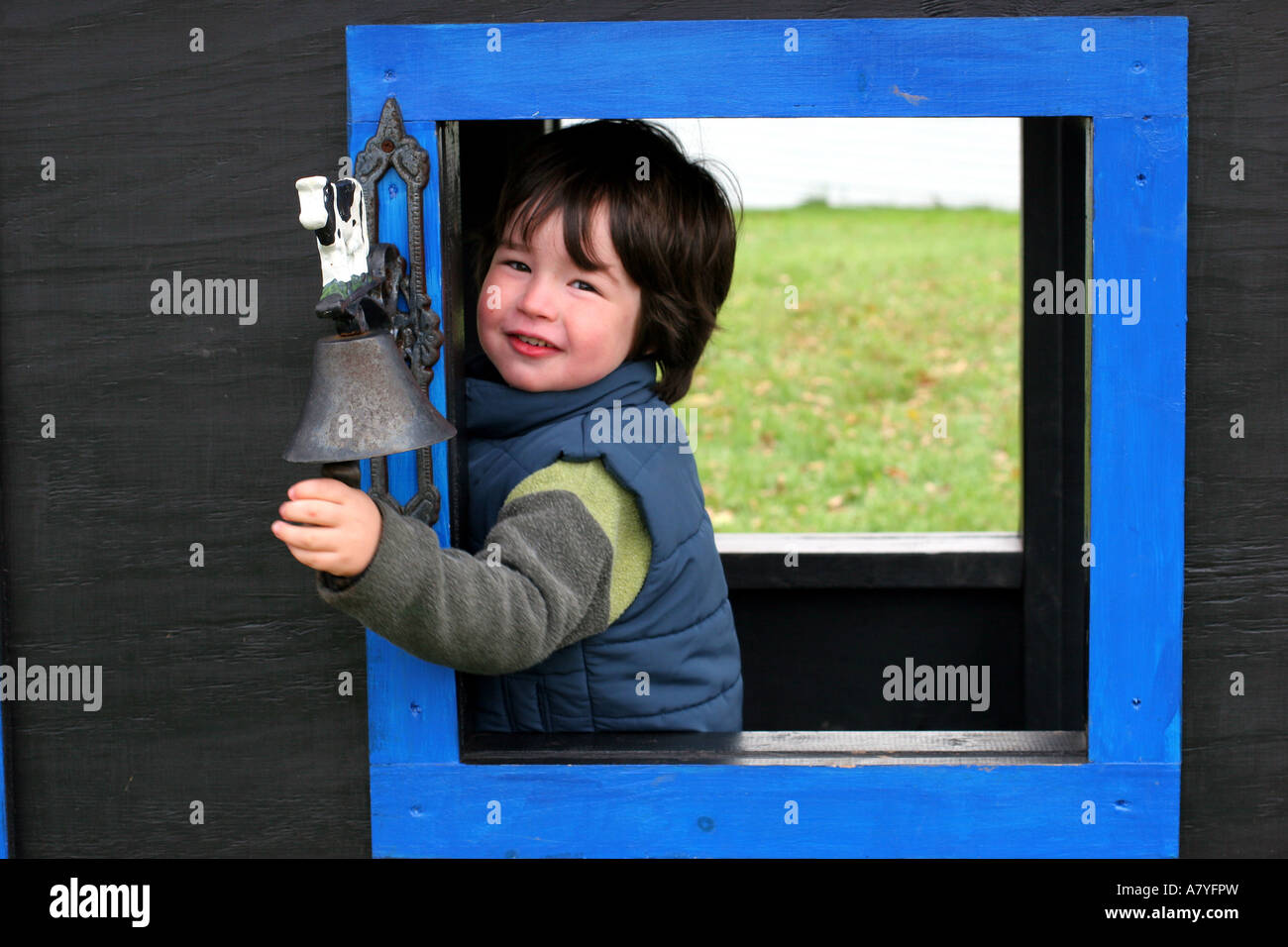 Smiling boy (3-4) cloche qui sonne sur une maquette en bois train Banque D'Images