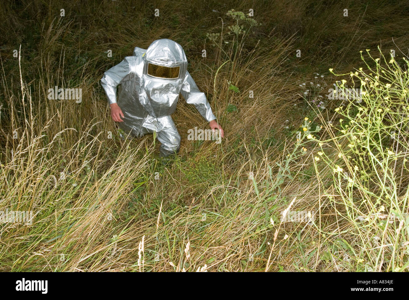 Un homme en costume de pompier en montée trekking au milieu de l'herbe sèche. Banque D'Images