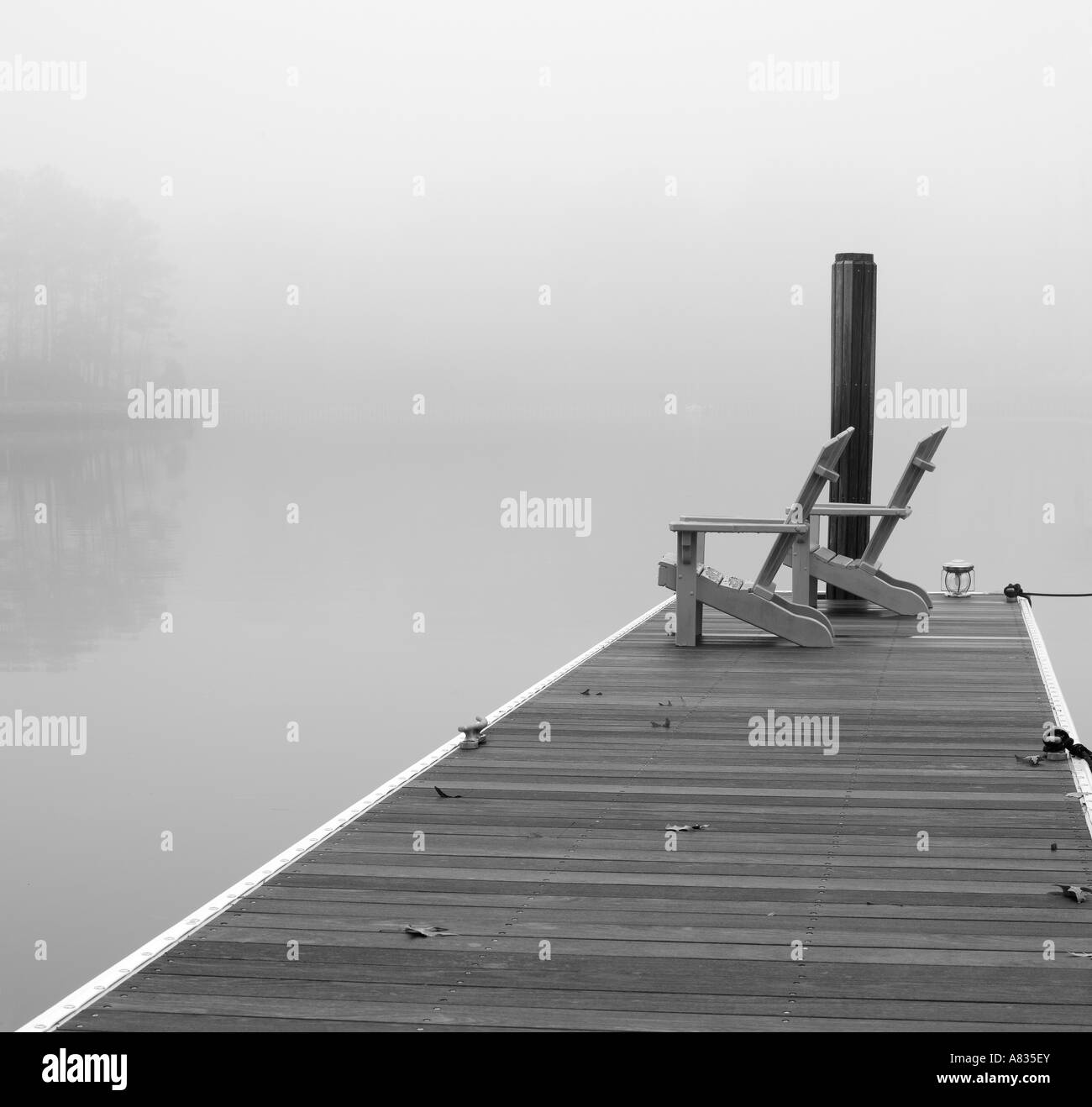 Chaises Adirondak dock sur le lac brumeux avec en arrière-plan Banque D'Images
