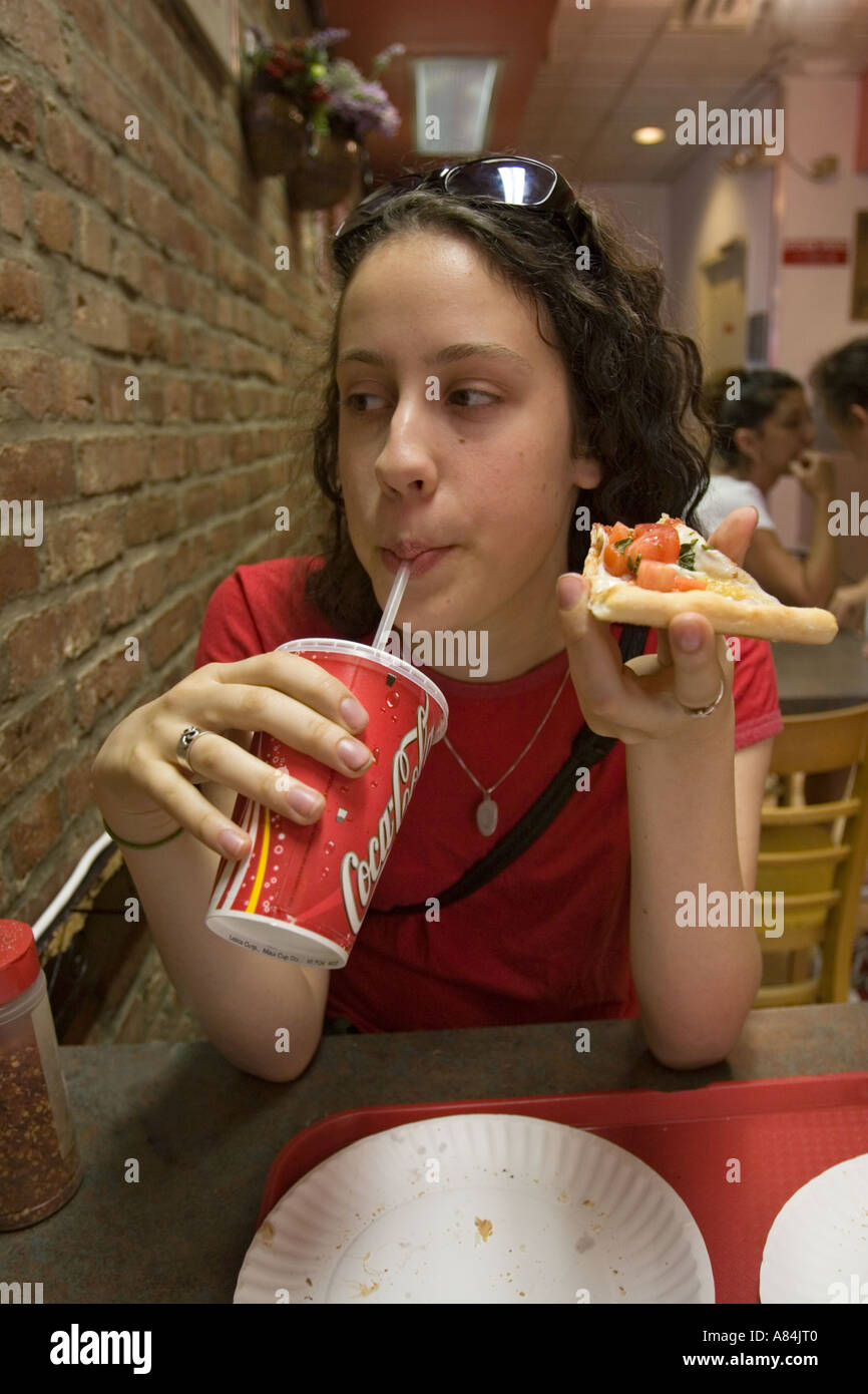 Adolescente ayant une pizza et une boisson gazeuse à Brooklyn New York Banque D'Images