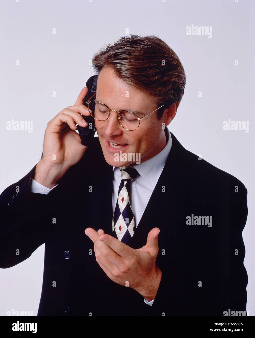 Studio portrait de jeune homme portant costume sombre et parlant au téléphone. Banque D'Images