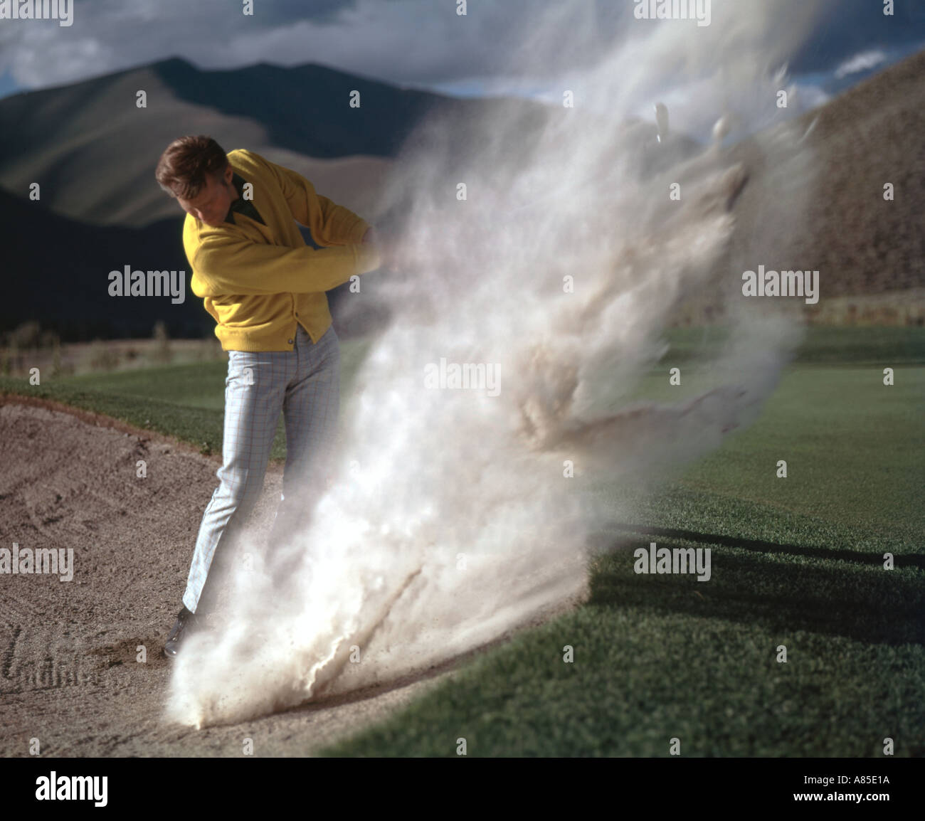 Golfeur Expert souffle un nuage de sable comme il joue sa balle d'un bunker Banque D'Images