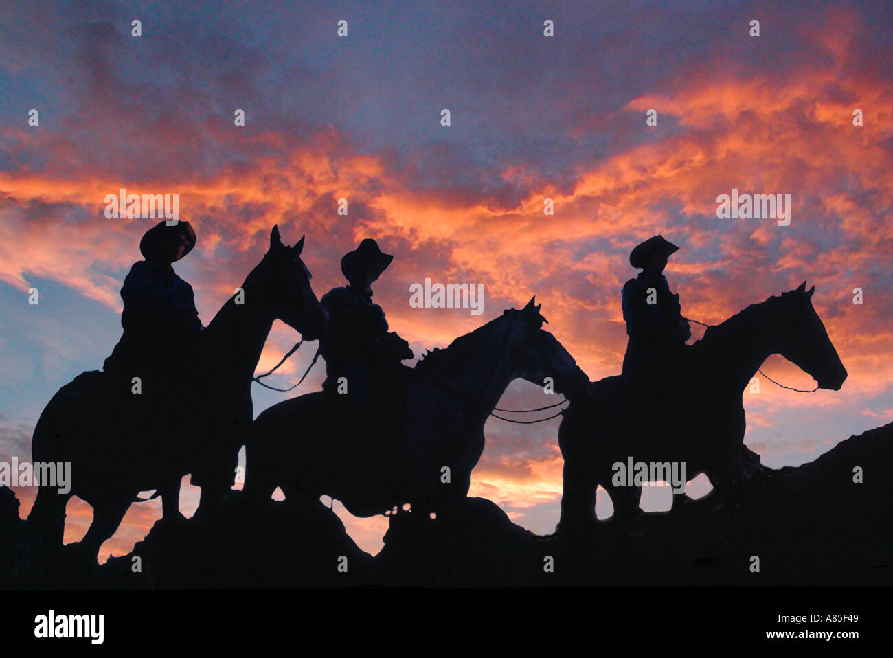 Trois cowboys l'équitation au coucher et au lever du soleil Banque D'Images