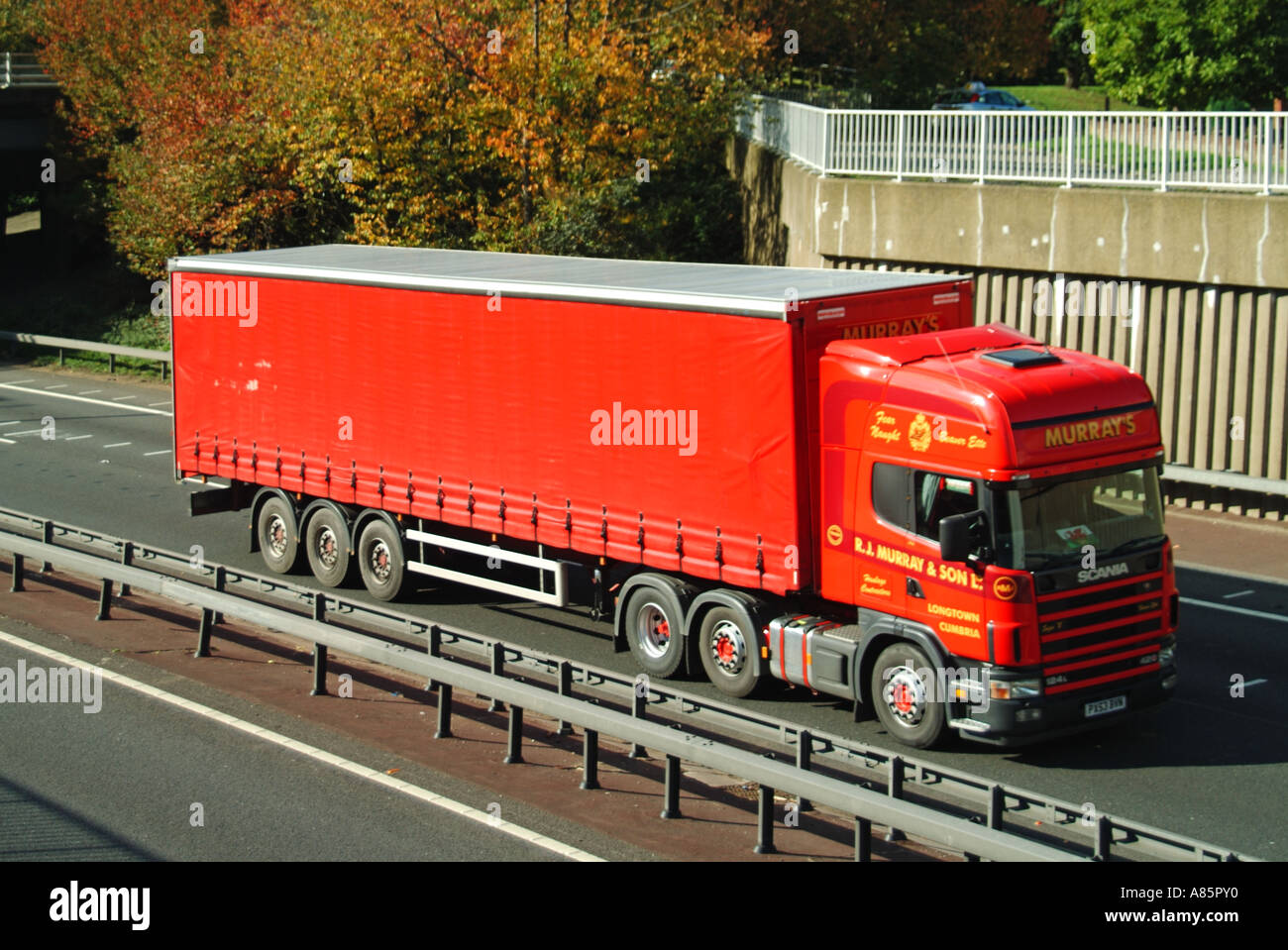 Vue latérale avant, camion de transport rouge et rideau coulissant souple sur remorque articulée, conduite sur route à deux voies au Royaume-Uni sur la route à coffre A12 Banque D'Images