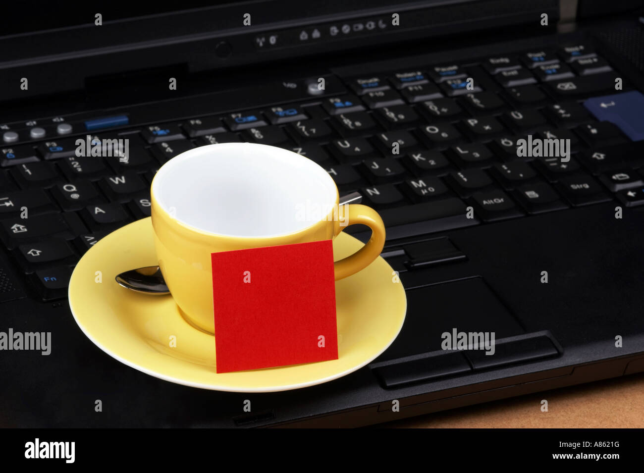 Espresso cup jaune rouge avec des post-it sur le clavier d'un ordinateur portable noir Banque D'Images