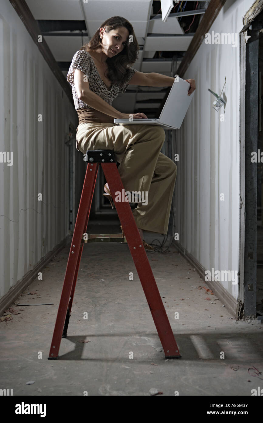 Vue d'une femme assise sur une échelle. Banque D'Images