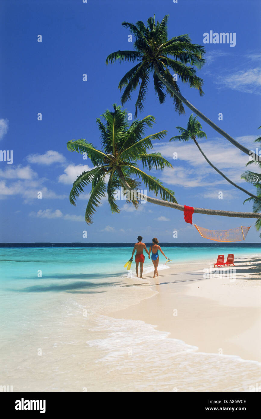 Couple marche main dans la main sur sandy shore sur l'île de Soneva Gili aux Maldives Banque D'Images