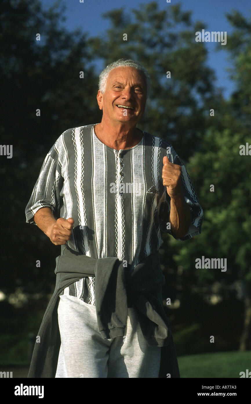 A smiling Senior citizen heureux 73 ans ans d'exécution du jogging dans le parc monsieur ©Myrleen POV Pearson Banque D'Images