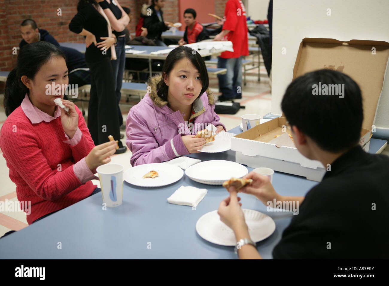 Les filles (16-17) avec boy (16-17) eating pizza in canteen Banque D'Images
