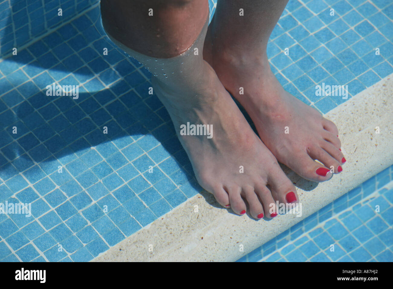 Pieds de femme en piscine avec orteils peints Banque D'Images