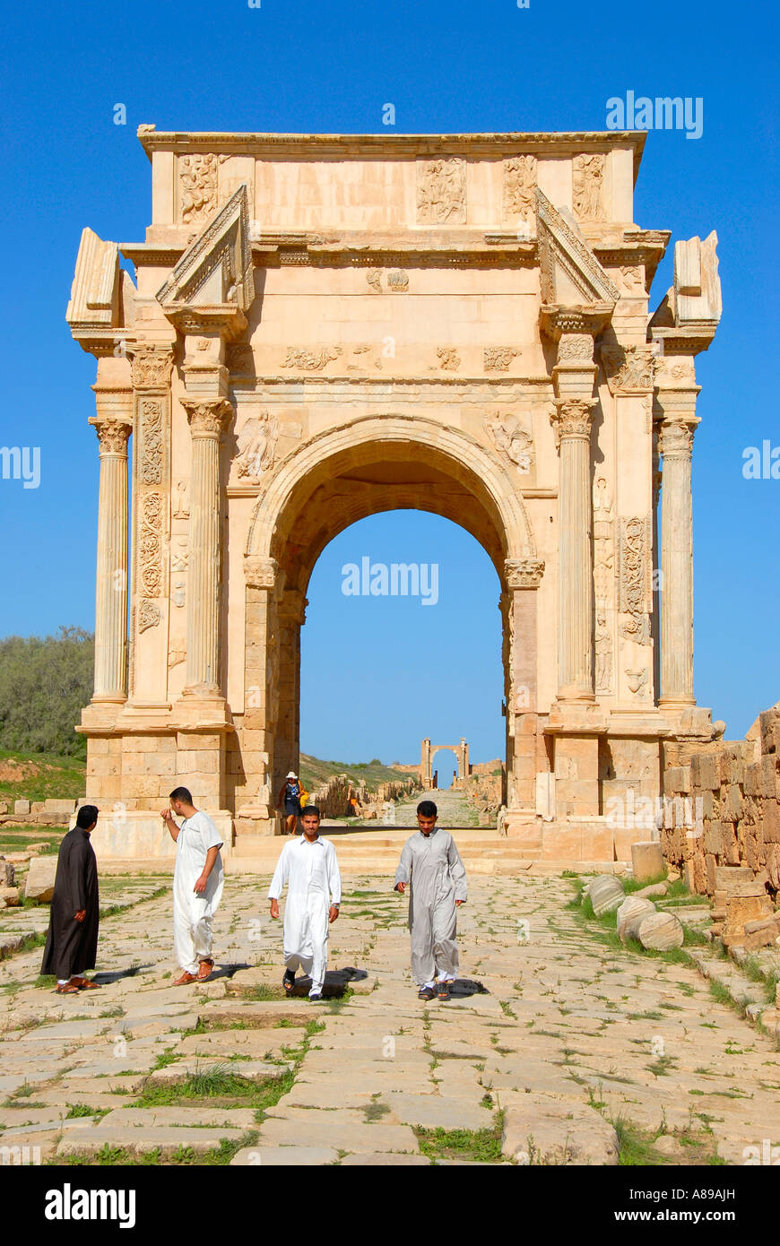 Quatre hommes sur le decumanus à arc de triomphe de Septime Sévère Leptis Magna Libye Banque D'Images