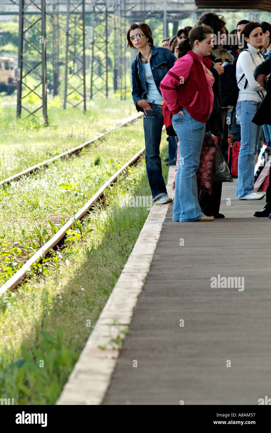 Groupe de personnes debout sur un quai de gare en attente d'un train Banque D'Images