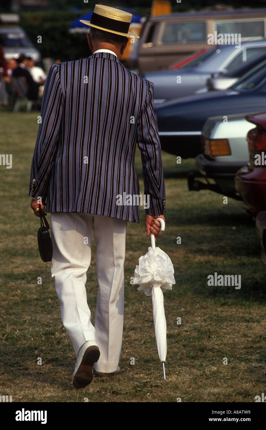 Homme des années 1980 en chapeaux de cratère de paille et blazers de club  d'aviron à Henley Royal Regatta, portant le parasol Henley de sa femme sur  Thames 1985 UK HOMER SYKES