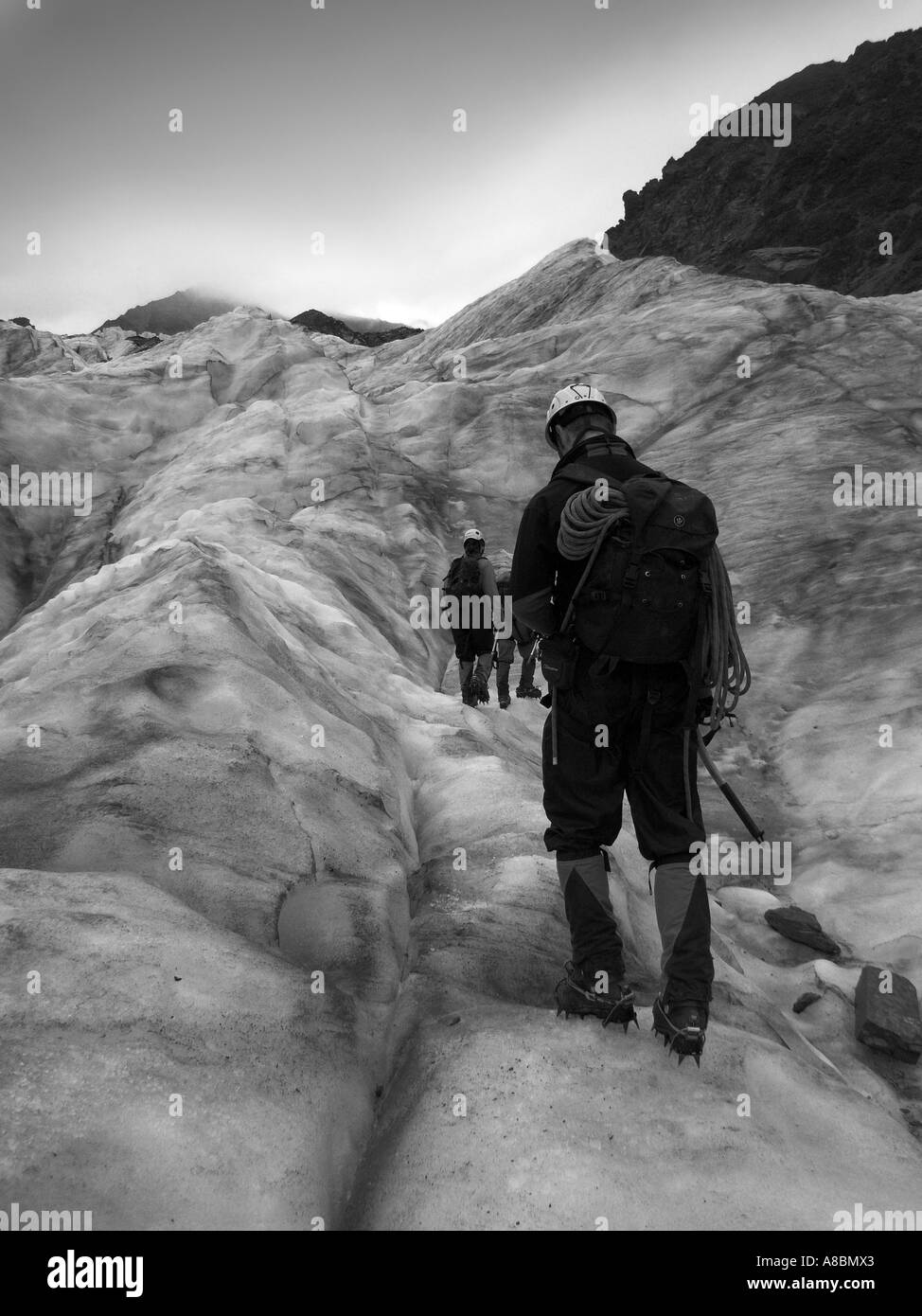 Une image en noir et blanc d'un membre de voyage walking up Fox glacier, île du Sud, Nouvelle-Zélande. Banque D'Images