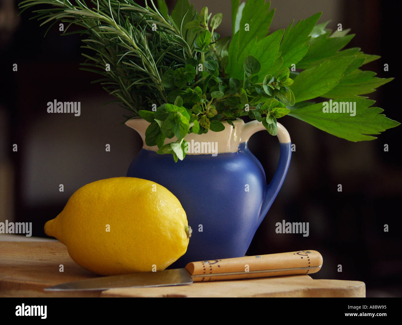 Blue cruche d'herbes du jardin avec le citron et le couteau sur planche de bois Banque D'Images