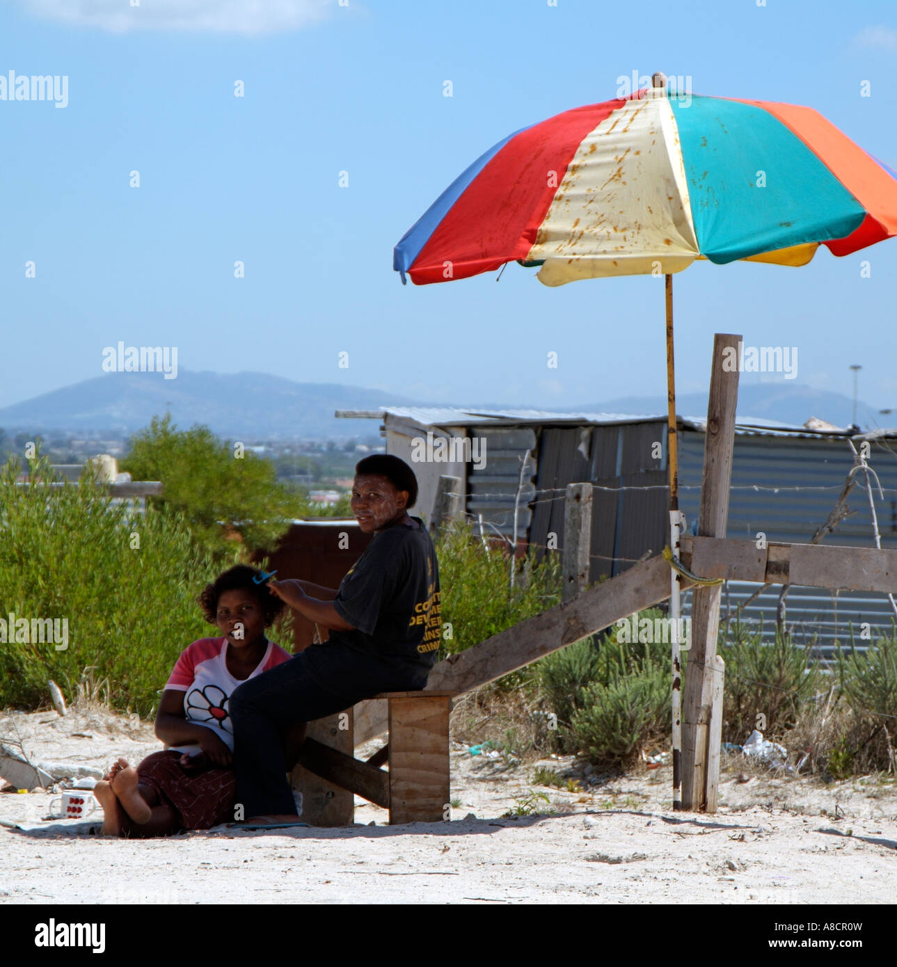 Township de Khayelitsha à la périphérie de Cape Town Afrique du Sud RSA Coiffure travaillant sous un vieux parapluie parasol Banque D'Images