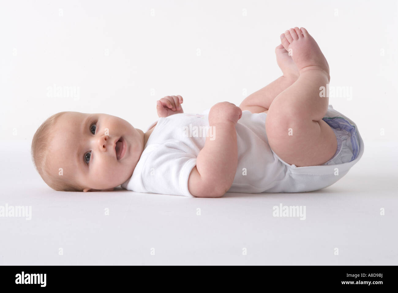 Heureux bébé couché sur le sol les pieds Banque D'Images