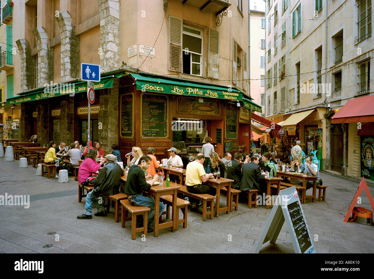 Manger dehors dans un coin boutique vendant la socca niçoise traditionnelle, - une crêpe de farine de pois chiches dans la vieille ville de Nice, France Banque D'Images