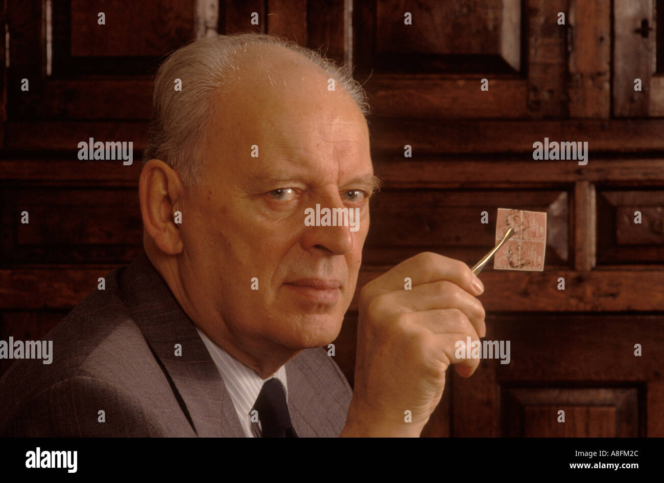 John Marriott, un collectionneur de timbres chez lui avec un groupe De 4 timbres rares années 90 précieux si tenir doucement avec Une paire de pinces UK HOMER SYKES Banque D'Images