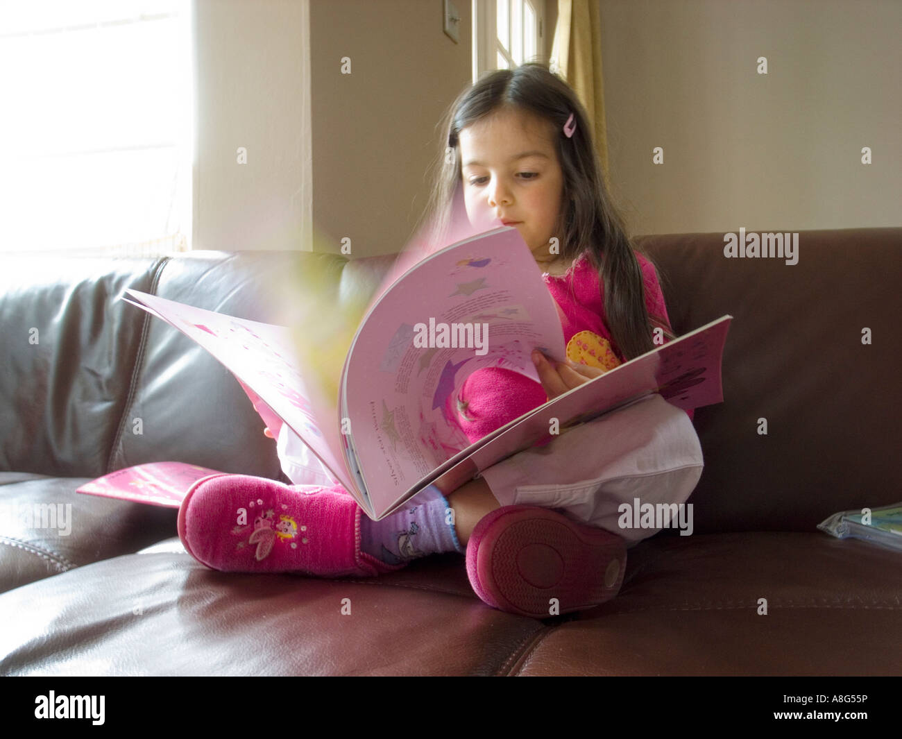 Girl reading book at home Banque D'Images