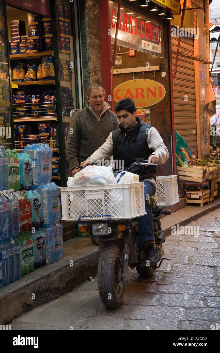 Propriétaire de boutique donne des instructions à la livraison sur garçon motorscooter marché Vucciria à Palerme Sicile Italie Banque D'Images