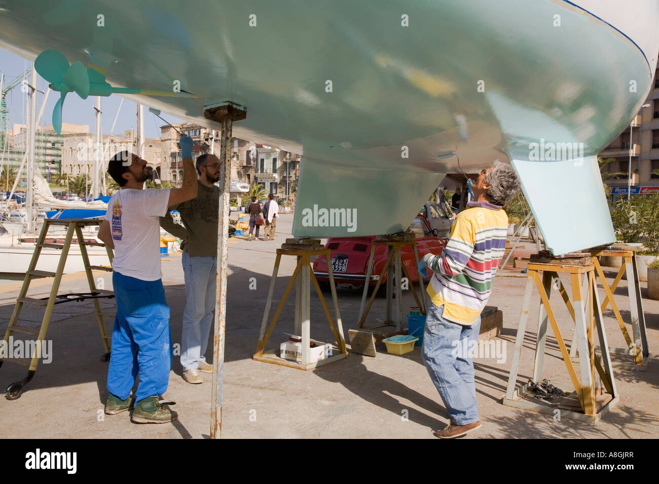 Peinture hommes bas de voilier coque avec rouleaux à peinture Marina à La Cala Palerme Sicile Italie Banque D'Images