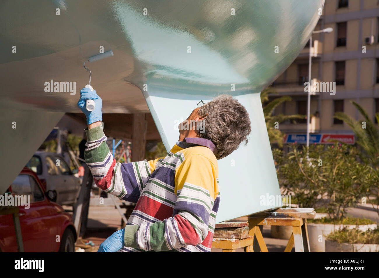 Man painting bas de voilier avec rouleau à peindre la Cala Marina à Palerme Sicile Italie Banque D'Images
