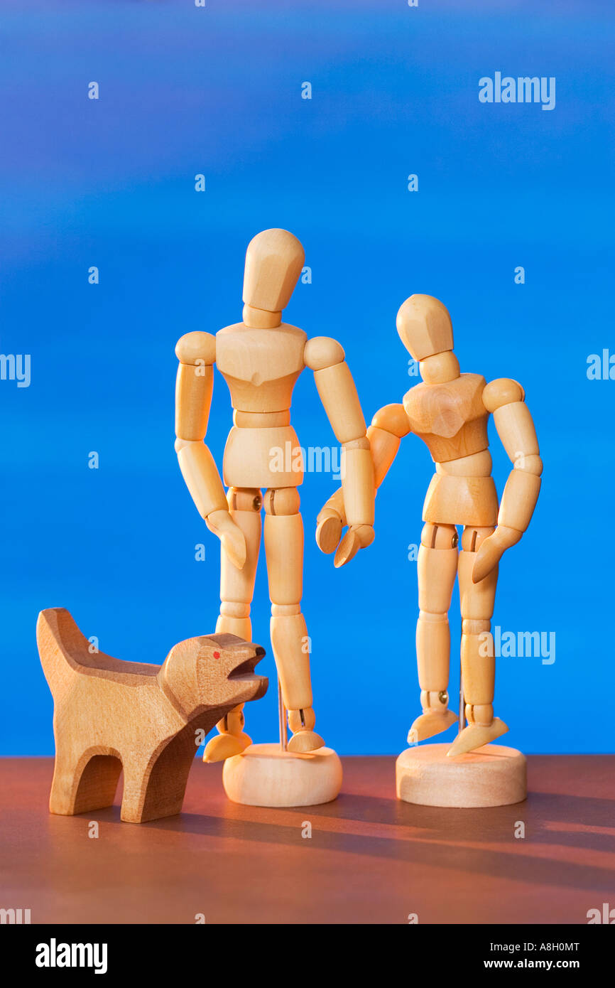 Homme et femme figures en bois avec figurine chien, sur un fond bleu. Banque D'Images