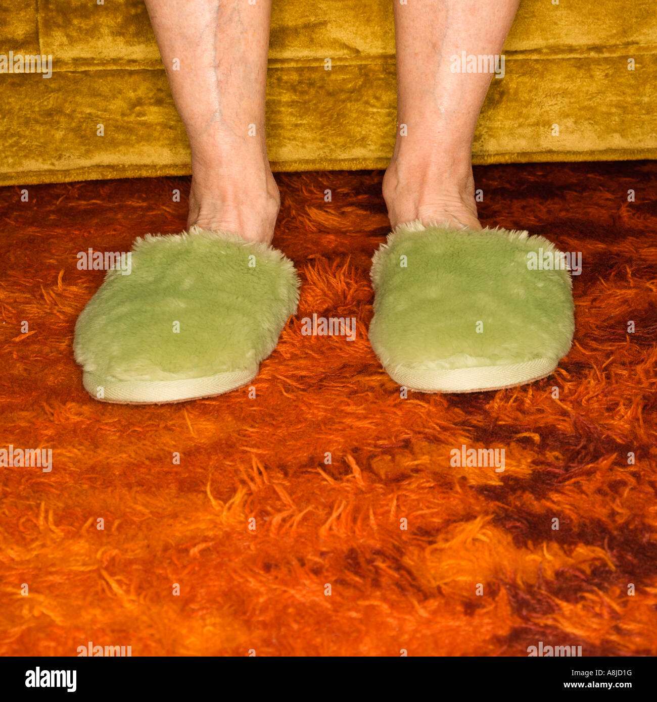 Caucasian female pieds portant des pantoufles sur tapis vert Banque D'Images