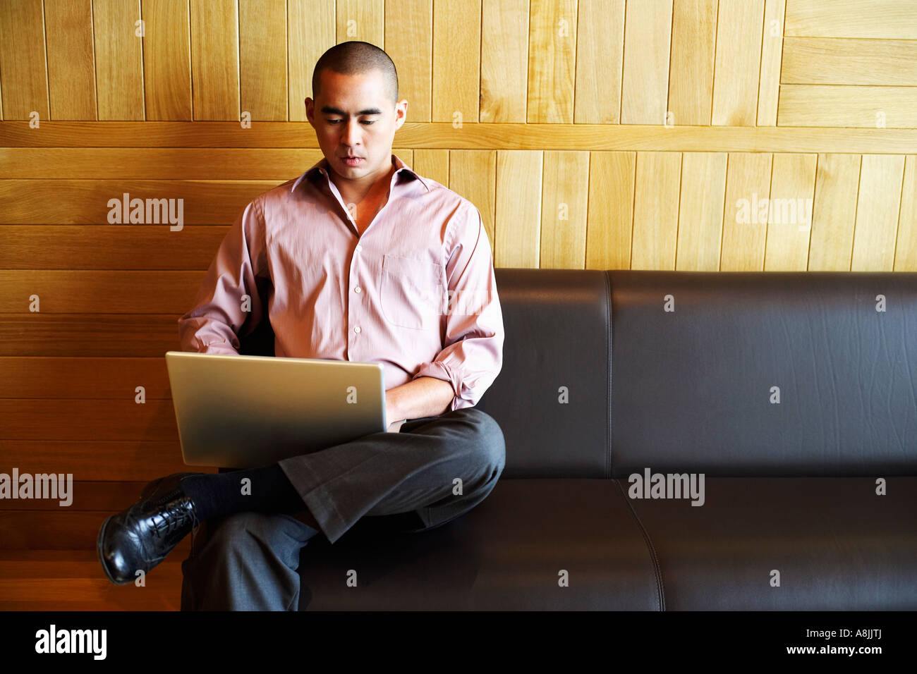 Portrait d'un jeune homme assis sur un canapé et à l'aide d'un ordinateur portable Banque D'Images