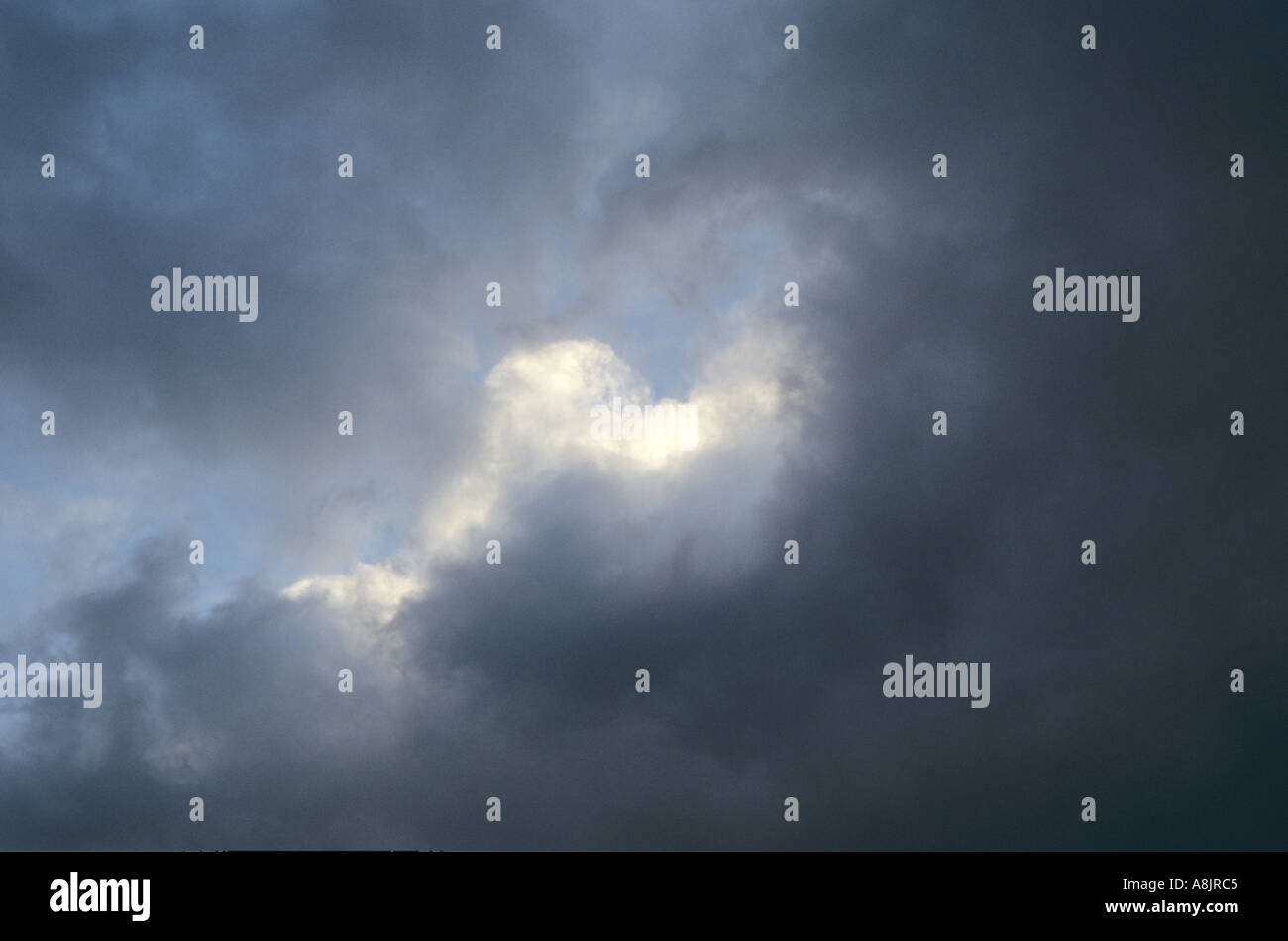 Cumulus blanc englouti par ou en les détachant de cumulus noir en fin d'après-midi avec ciel bleu Banque D'Images