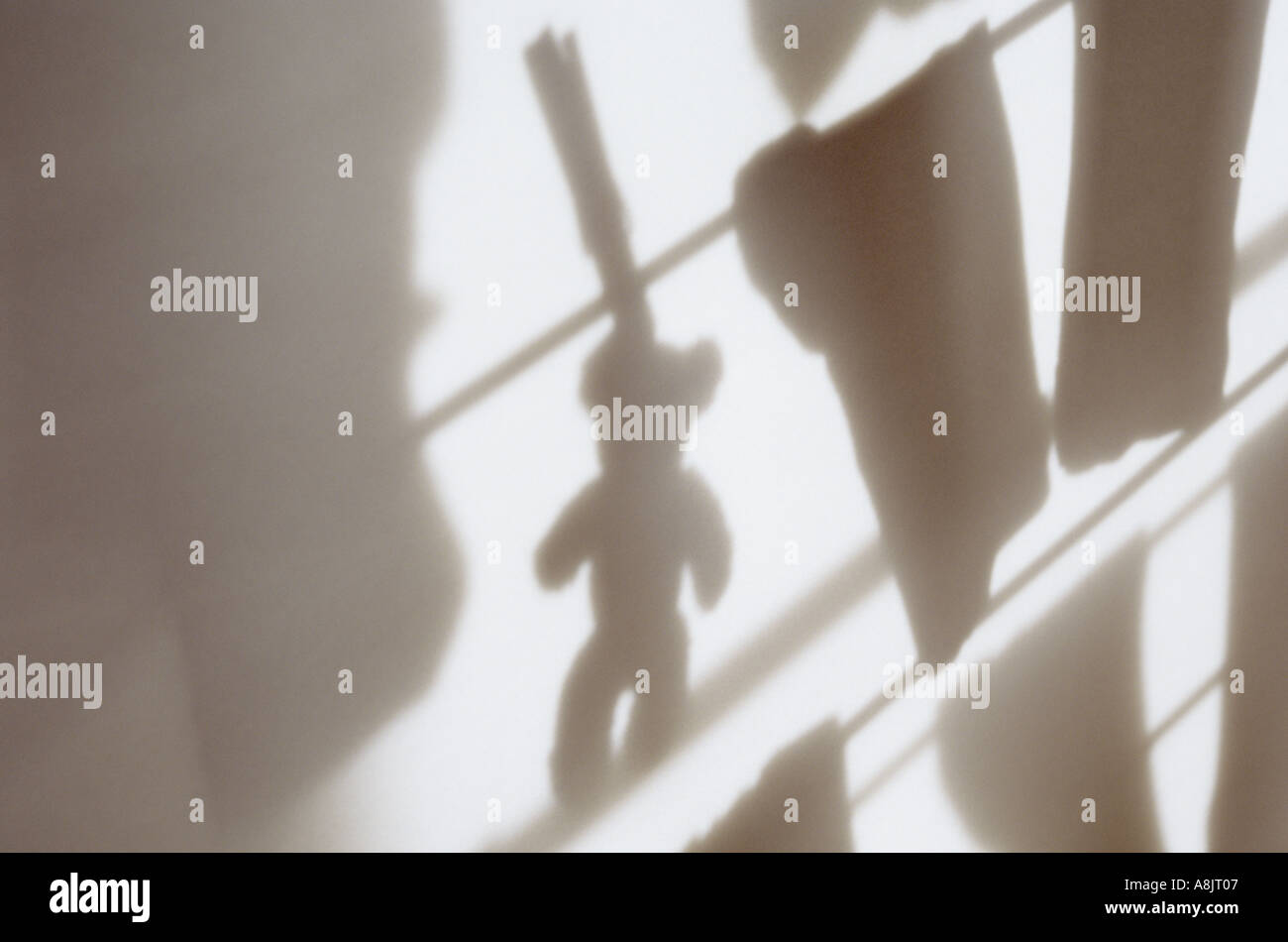 Ombre d'un petit ours en peluche et des chaussettes avec les autres vêtements en train de sécher dehors sur un porte manteau Banque D'Images