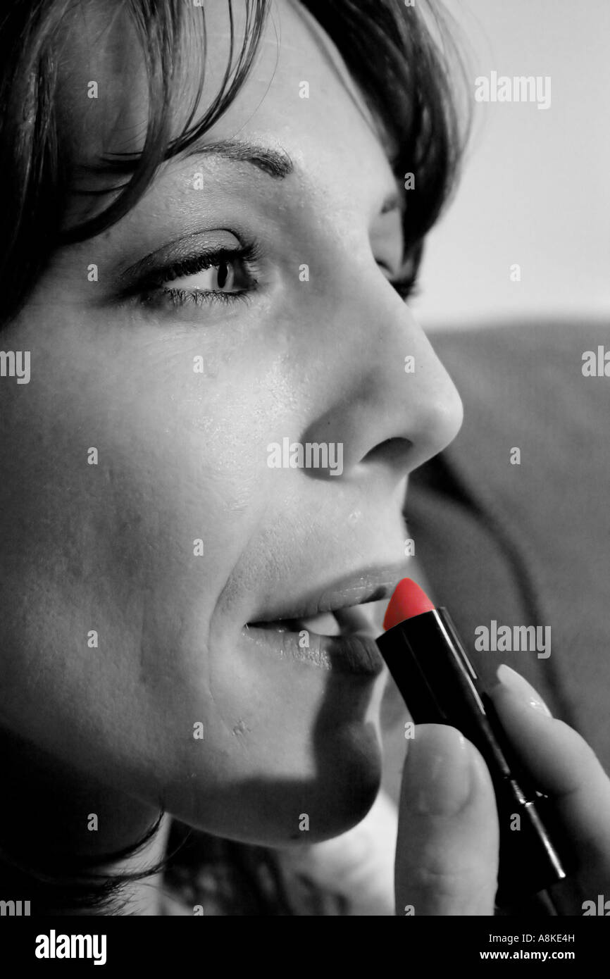 Le noir et blanc mélangé avec photographie couleur de woman applying lipstick Banque D'Images
